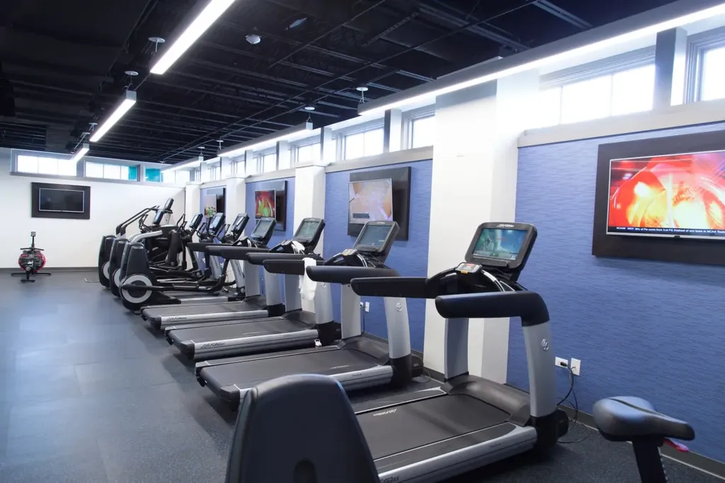 Modern fitness center with row of treadmills and touch screens