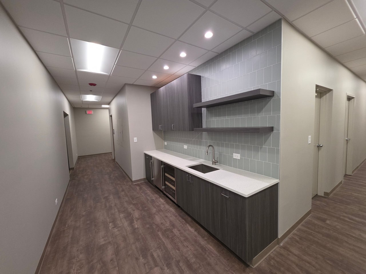Compact kitchenette with gray tile wall and floating shelf