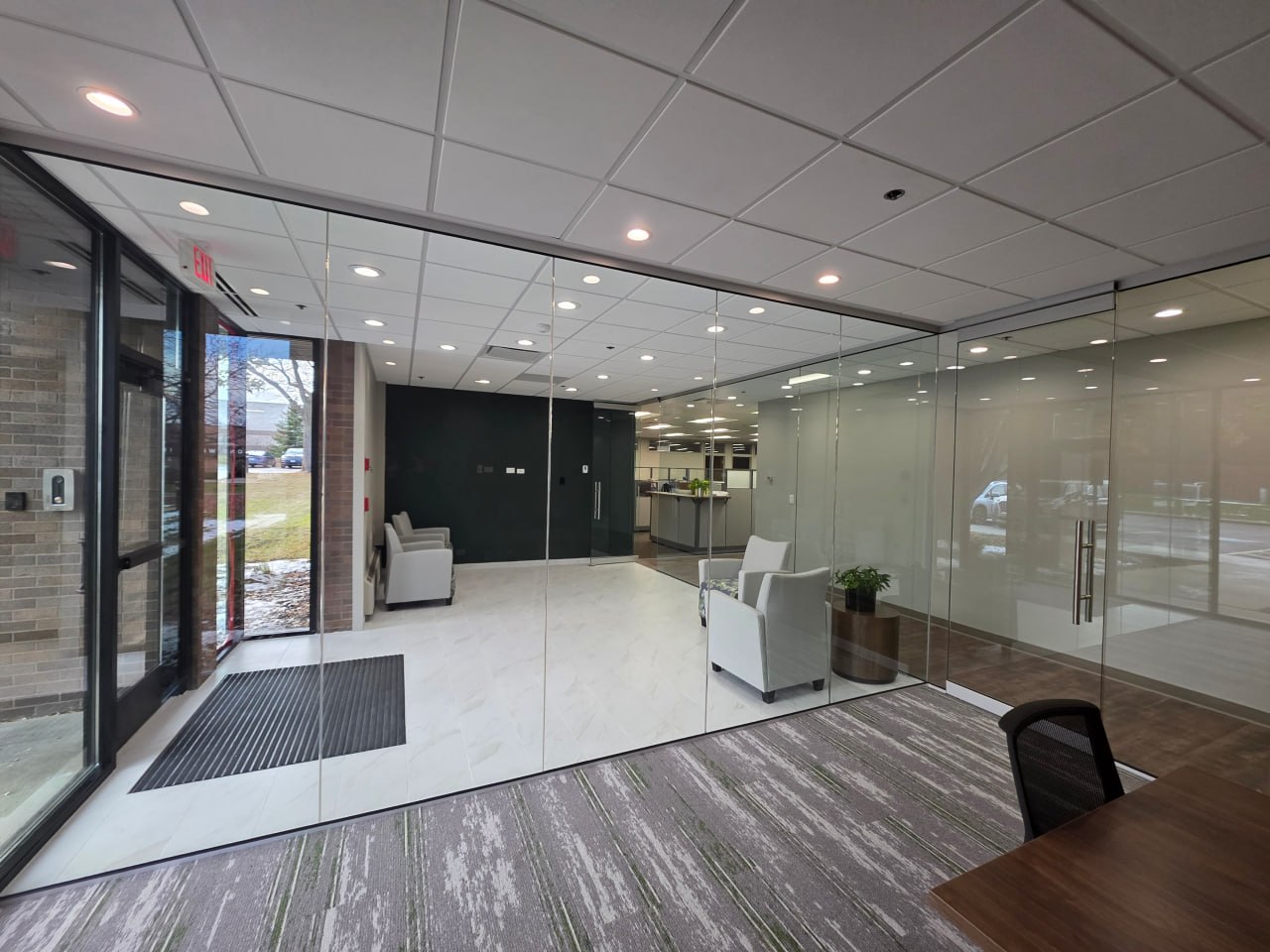 Office reception area with glass partition and waiting chairs