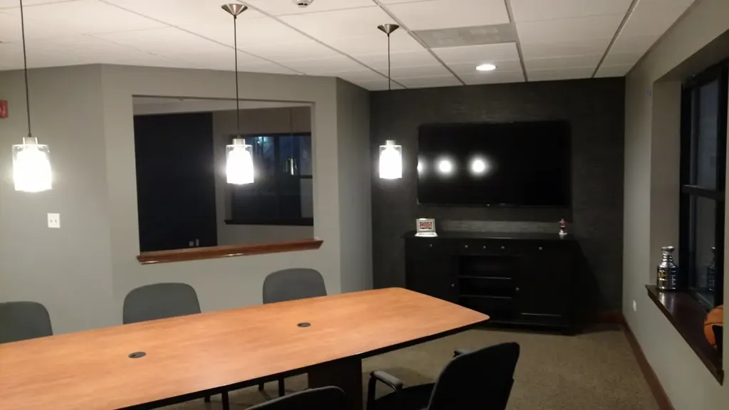 Modern meeting room with large table, pendant lights, and dark wall